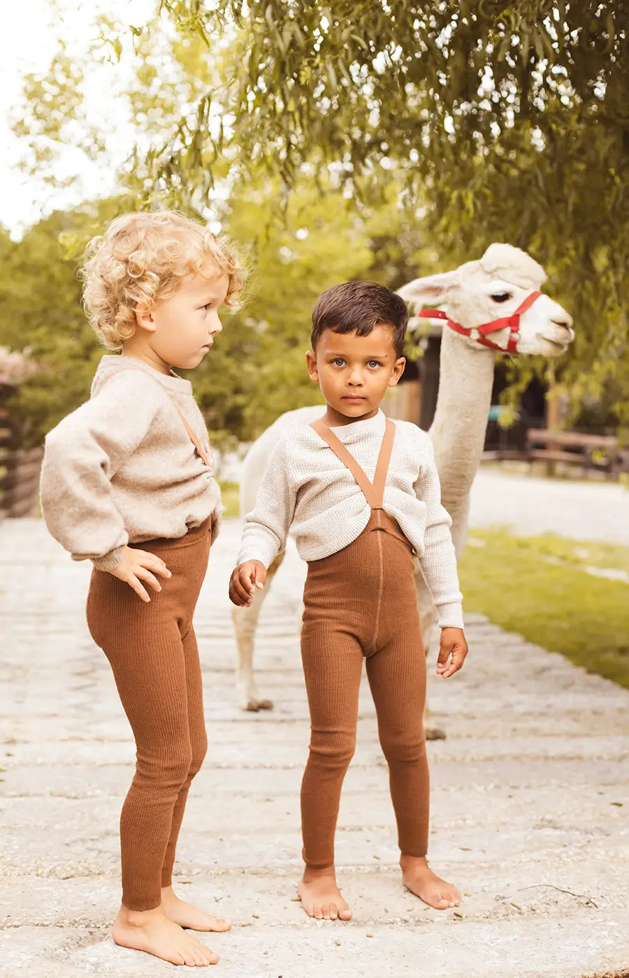 Dvě malé děti oblečené do dětských pančuch PEQNE v hnědé přírodní barvě, pohodlné a měkké oblečení pro každodenní nošení venku