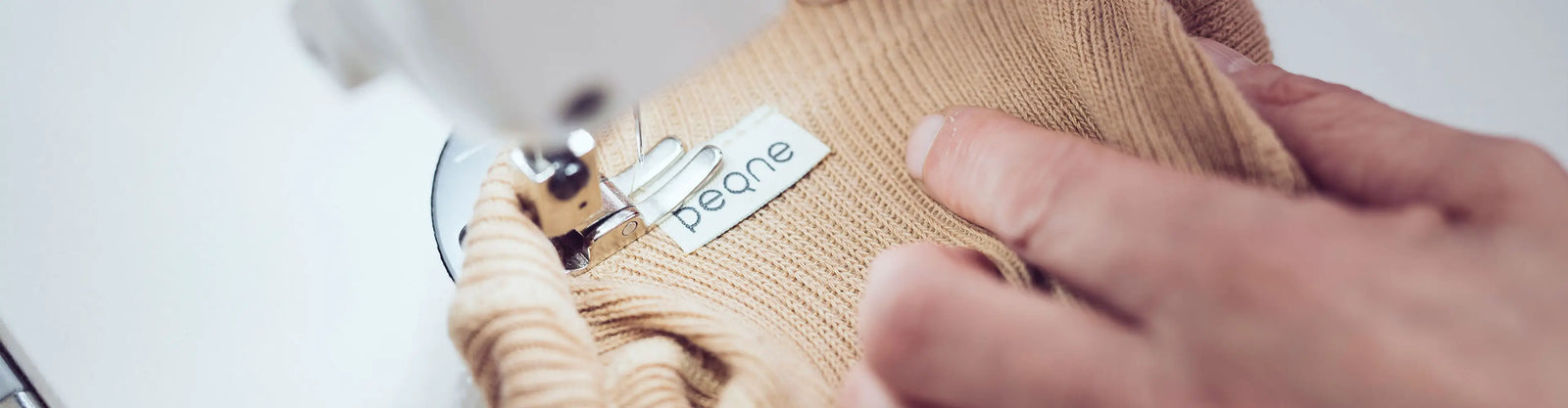 Detail šitia detských pančúch PEQNE, prišívanie značkového štítku na mäkký úplet počas ručnej výroby